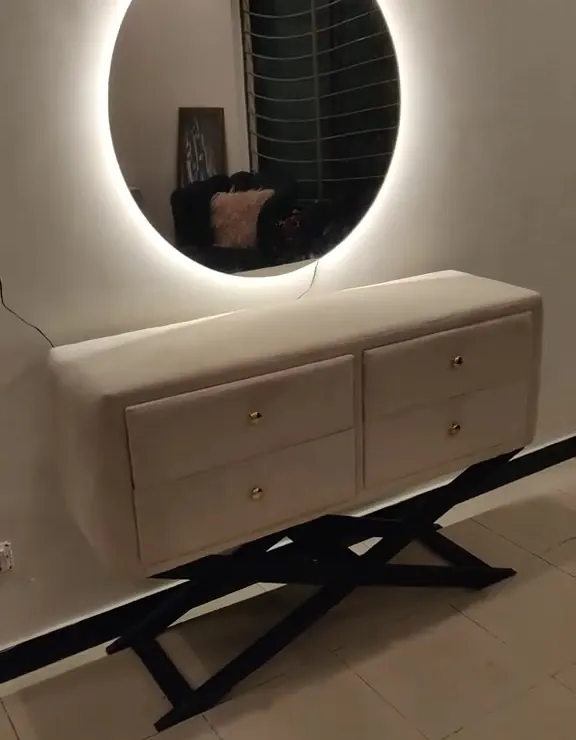 Upholstered console with drawers under a round lit mirror